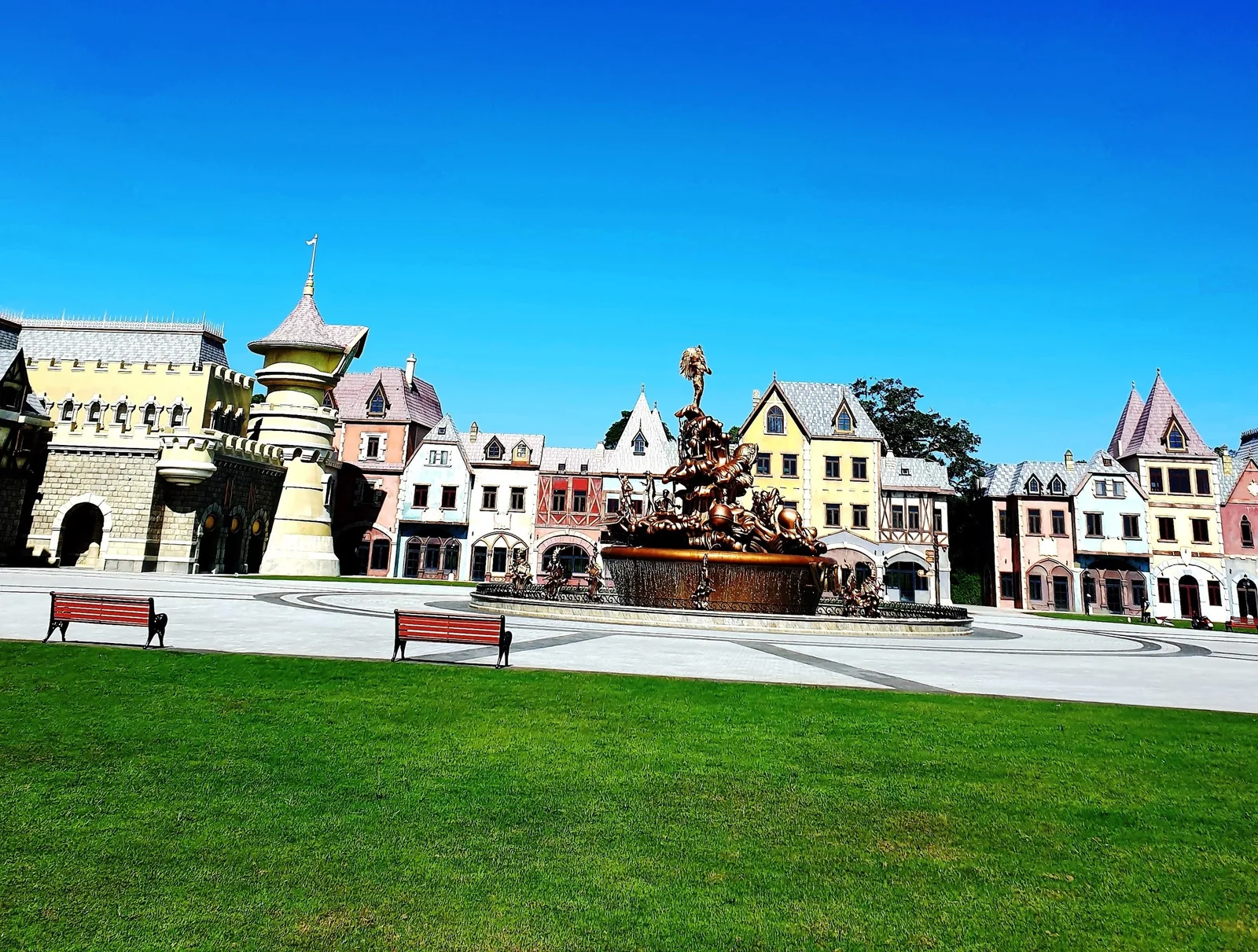 A European-style plaza with colorful gabled houses and a bronze fountain under a clear blue sky in Phu Quoc. A European-style plaza with colorful gabled houses and a bronze fountain under a clear blue sky in Phu Quoc.