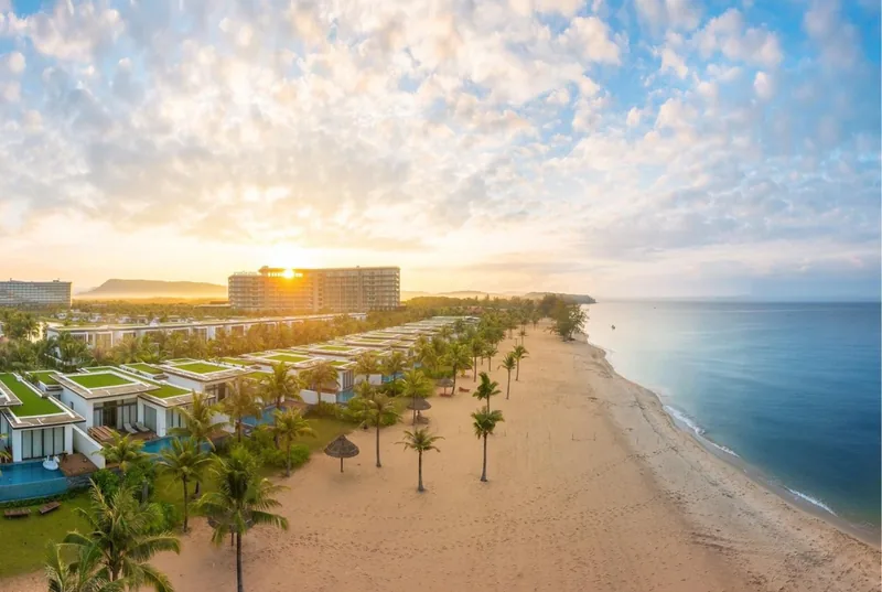 Aerial sunrise view of a beachfront resort with palm trees and villas along a sandy shore in Phu Quoc Aerial sunrise view of a beachfront resort with palm trees and villas along a sandy shore in Phu Quoc