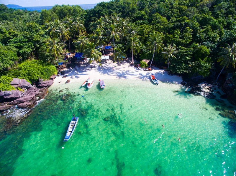 Aerial view of turquoise water, white sand, and moored boats along a palm-fringed cove in Phu Quoc. Aerial view of turquoise water, white sand, and moored boats along a palm-fringed cove in Phu Quoc.